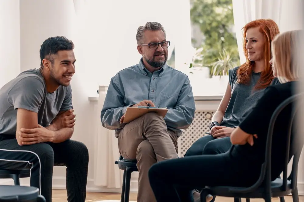 A group of young adults discussing their experiences with anxiety during a group therapy session.