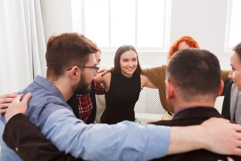 A group of professionals and peers showing support for one another during a therapy session.