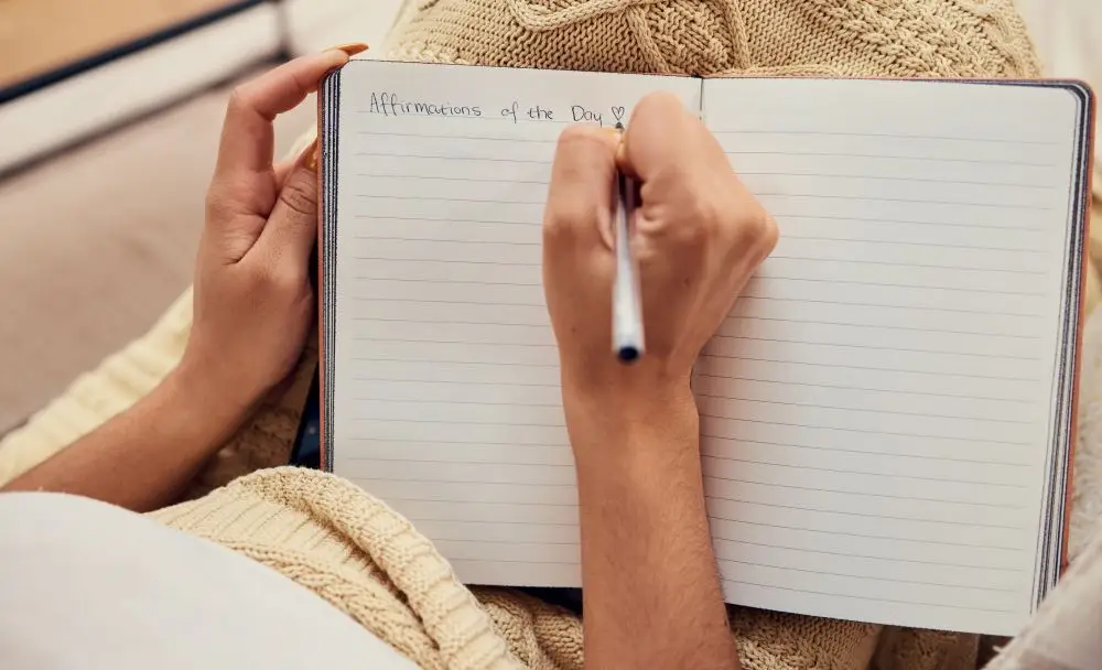 A women writing in a journal expressing her affirmations for the day.