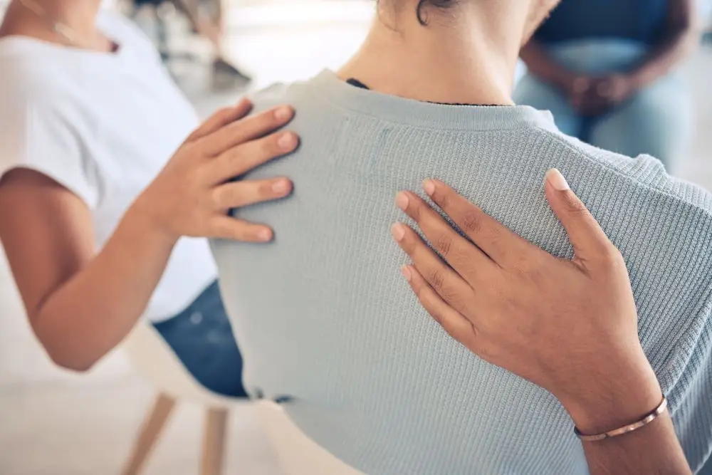 A woman in therapy being supported by her peers.