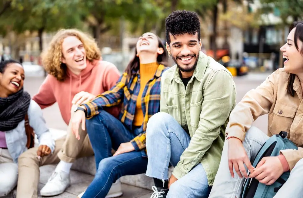 A group of young adults hanging out at a park and laughing together.